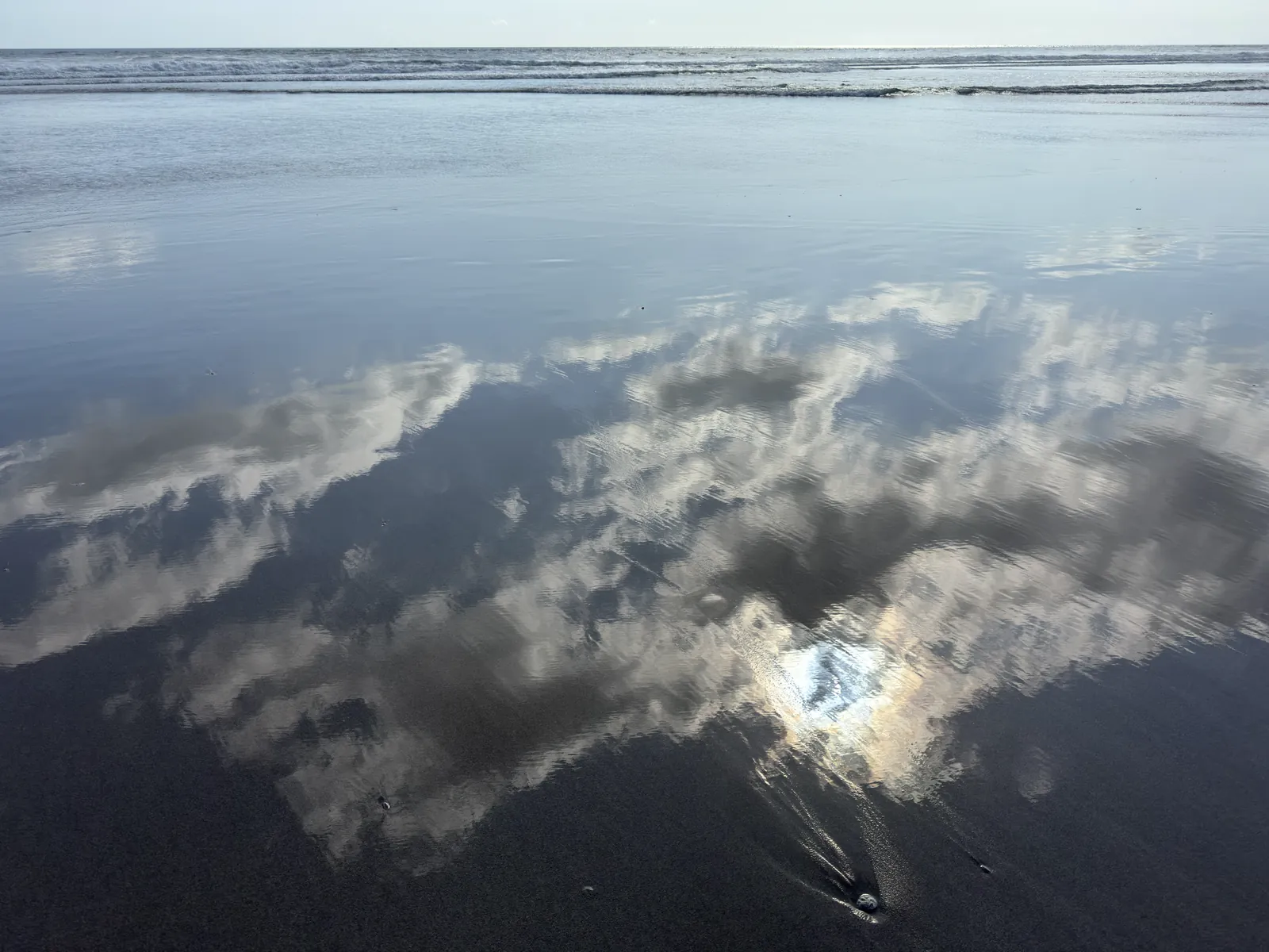 Clouds reflected on wet sand on Seminyak beach